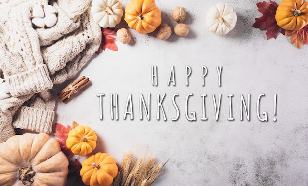 Thanksgivings and autumn composition. Pumpkin with cotton flowers, autumn leaves, sweater and the text on stone background.