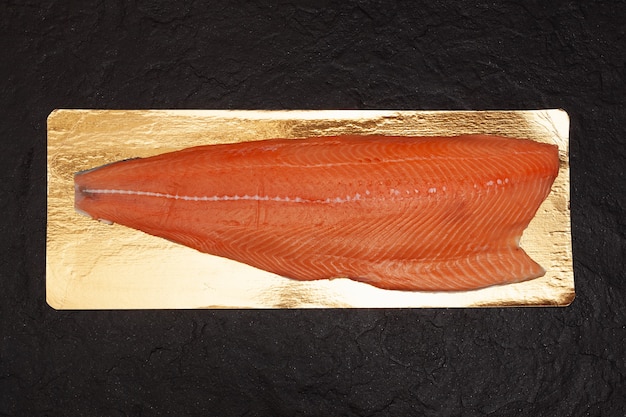 Photo thawed salmon or sockeye salmon fillet on a dark textured stone background