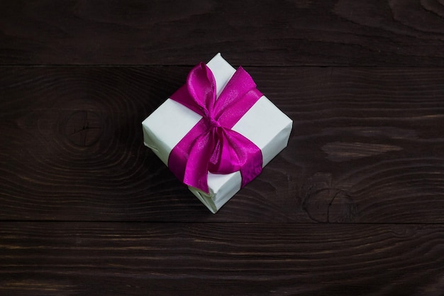 Theme of celebrations and gifts exclusive gift Packed in white box with purple ribbon beautiful and expensive gift on dark wooden background