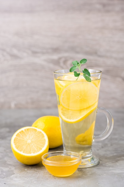 Therapeutic drink of lemon, honey and mint in a glass on the table. Alternative medicine, treatment with folk remedies.