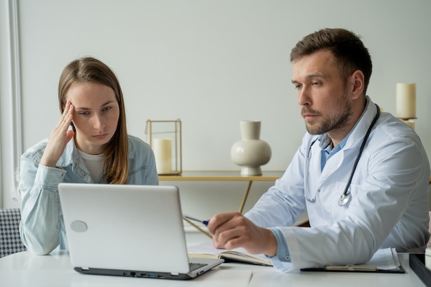 Therapist doctor man talking to patient adult male in white coat talks to female patient in medical office