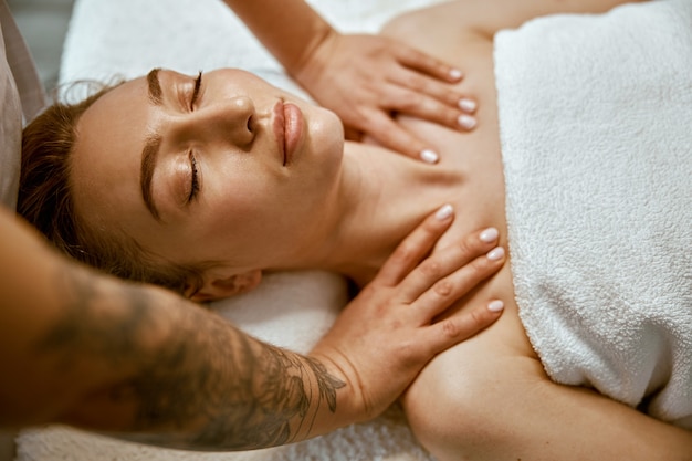 Therapist is doing face relaxing massage to a young woman in modern wellness cabinet