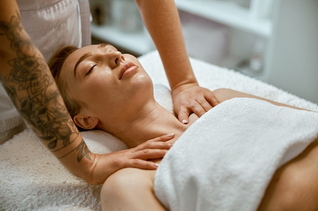 Therapist is doing face relaxing massage to a young woman in modern wellness cabinet