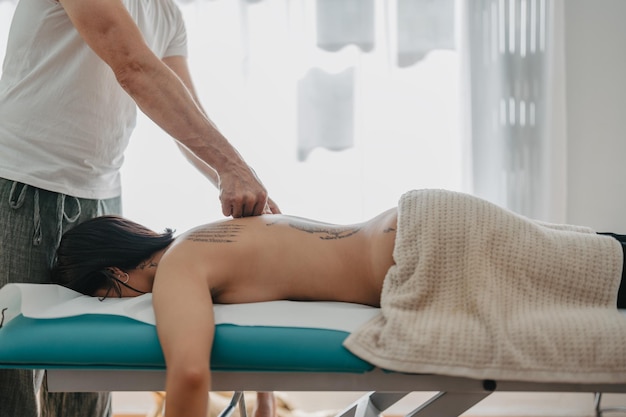 Therapist massages a woman39s vertebrae with his thumbs