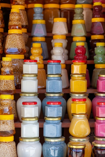 There are many jars of organic, natural honey on the counter for sale. Different honey, different colors in plastic cans are ready for sale at the honey fair. Nuts filled with honey.