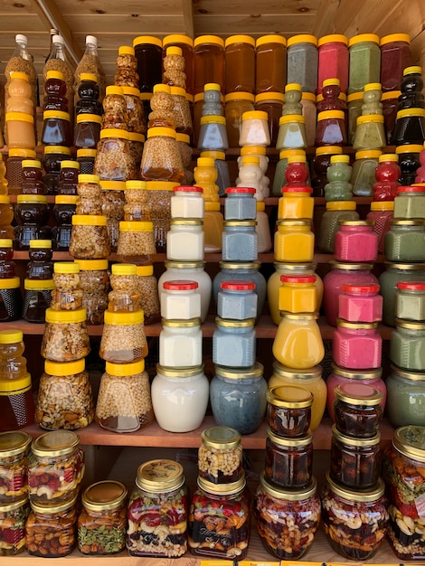 There are many jars of organic, natural honey on the counter for sale. Different honey, different colors in plastic cans are ready for sale at the honey fair. Nuts filled with honey.