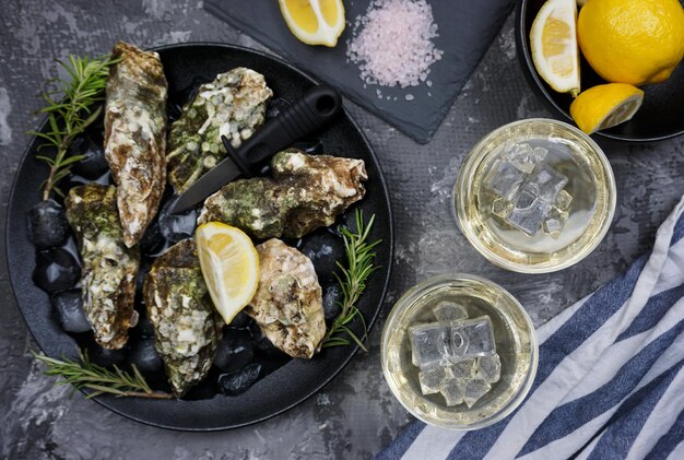 There are two glasses of white wine and freshly caught oysters on the table