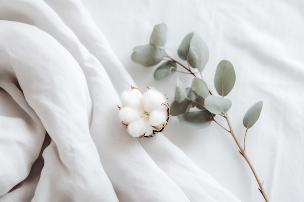 There is a cotton flower on a white sheet with a green branch generative ai