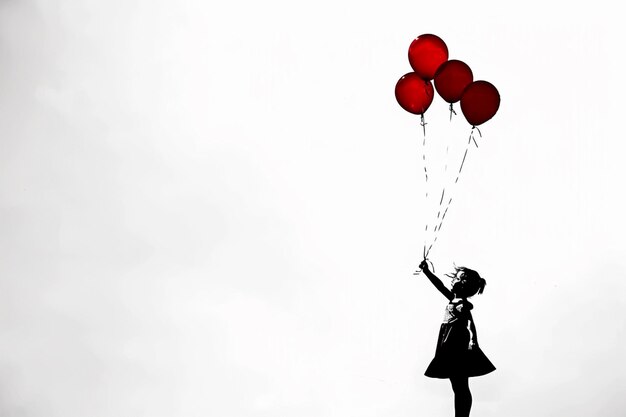 Photo there is a girl that is holding some red balloons generative ai