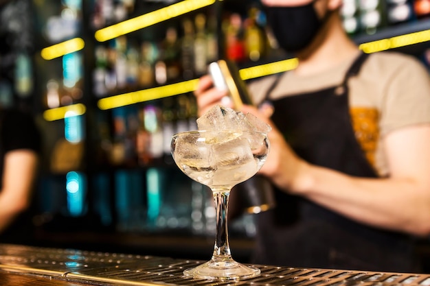 There is a glass with ice on the bar The glass is chilled before serving the cocktail Horizontal photo