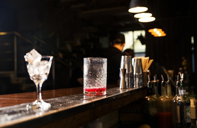 There is a glass with ice for a cocktail and a glass with a cocktail on the bar counter Cocktail making process Horizontal photo