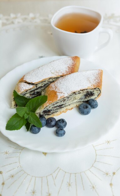 There is a plate of poppy seed cake on the table and a cup of tea next to it