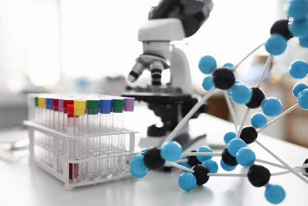 There is rack on table with many test tube with colorful lid and plastic molecule