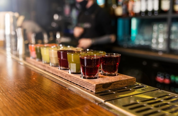 There is a wooden stand with shots on the bar counter There are different types of tinctures in the shots Horizontal photo