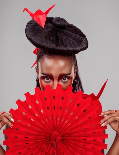 Theres a quiet power in a moment of silence Studio shot of a beautiful young woman wearing Asian inspired makeup and posing with a fan against a grey background