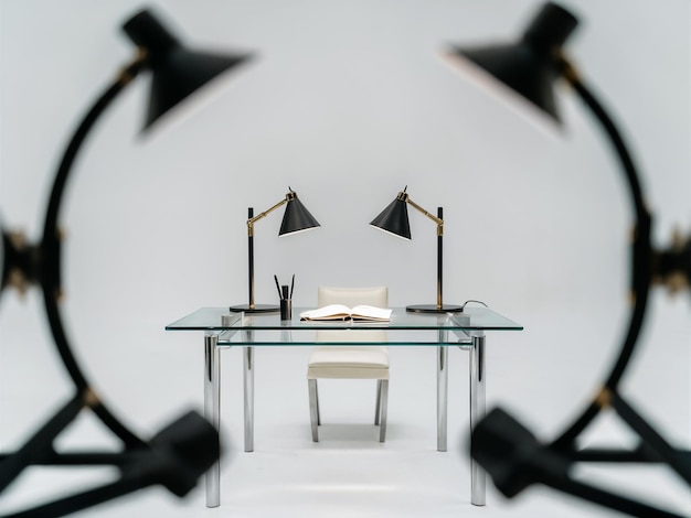 theres a sleek glass table with a few itemssuch as a modern lamp a black pen and a white notebook