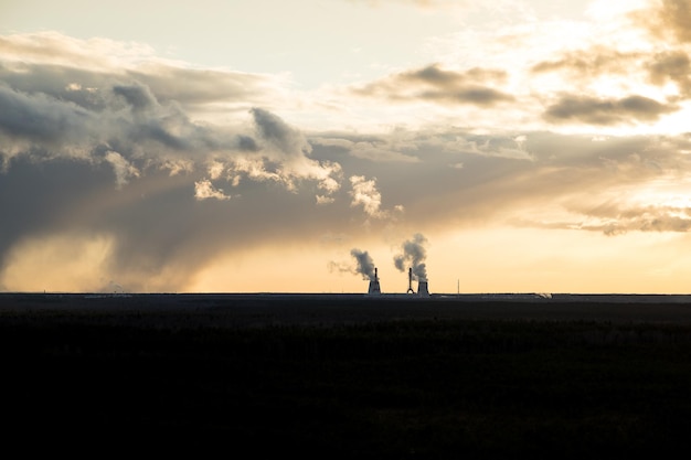 A thermal power station with much smoke coming out of pipes with dark dramatic sky over it Concept of air pollution alternative energy and natural gas production concepts