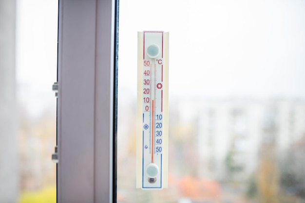 A thermometer attached to the window shows that it is 13 degrees Celsius outside, close-up