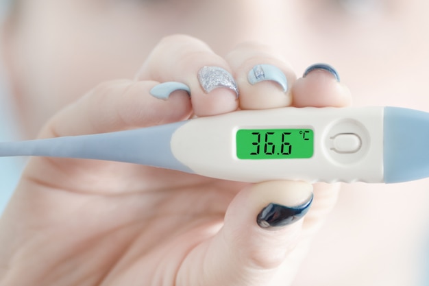 Thermometer in female hand. Normal body temperature.