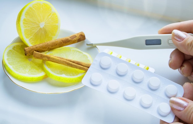 Thermometer in hands tablets lemon with cinnamon the concept of treatment of colds