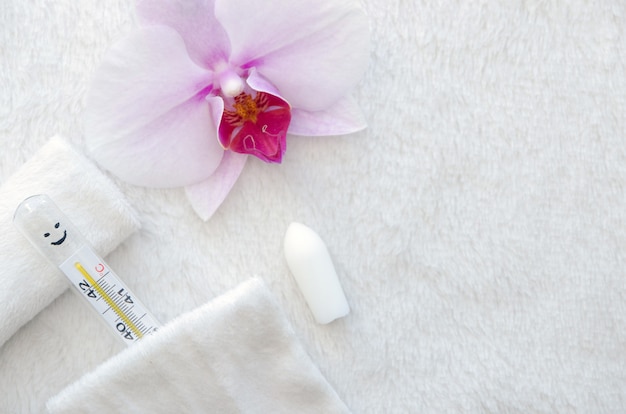 Thermometer on a pillow with an archidea flower and candles for sanitation.