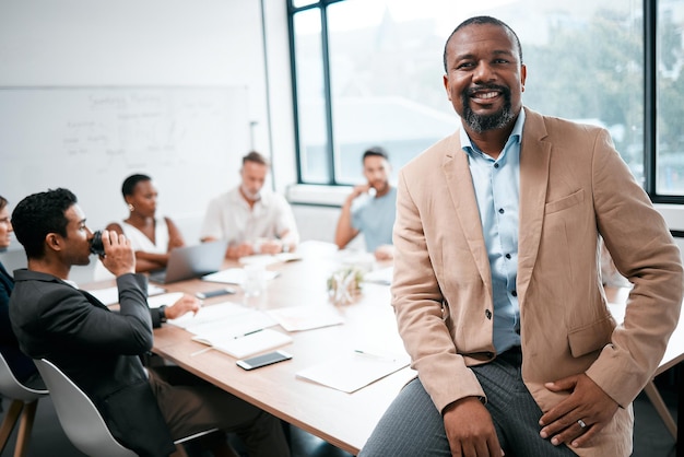 These meetings keep us all in sync Cropped portrait of a handsome mature businessman attending a meeting in the boardroom with his colleagues in the background