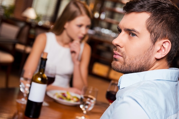 They have nothing more to say. Frustrated young man looking away while sitting together with his girlfriend in restaurant