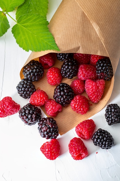 They look like artificial treats! But they are delicious and beautiful blackberries and fresh raspberries. Isolated on white background.