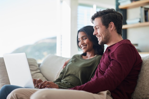 They put the we in weekend Shot of an affectionate young couple using their laptop while sitting on the sofa at home