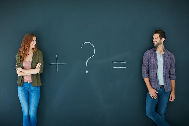 Theyve got a mysterious attraction Shot of a young couple standing in front of a blackboard with symbols written on it