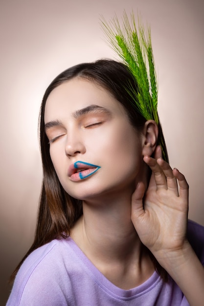 Thick eyebrows. Dark-haired model with thick eyebrows closing eyes while posing with spikelet in her hair