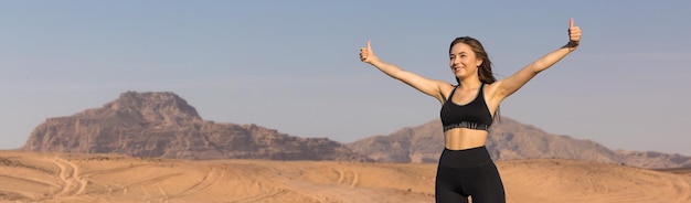 A thin athletic girl takes a break between classes on the background of mountains in the early morning