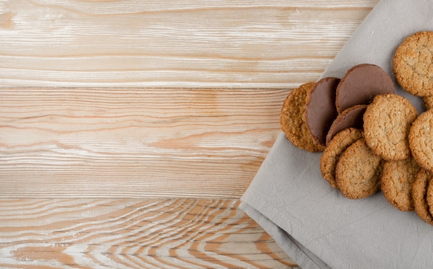 Thin oatmeal cookies or healthy cereal oat crackers with chocolate. Crispy anzac biscuit cookie with oat flakes on rustic table background top view