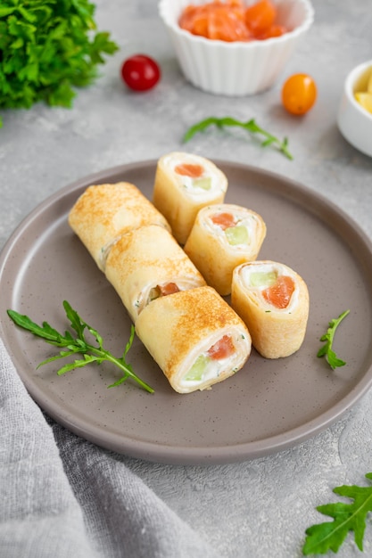 Thin pancake rolls or crepes rolls with smoked salmon cream cheese cucumber and dill