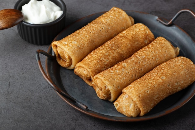 Thin pancakes or crepes stuffed with cottage cheese on grey background