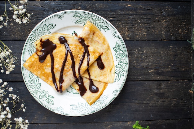 Photo thin pancakes pour chocolate crepes syrup white plate flat cake