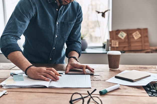 Thinking about every detail. Close up of young man drawing with ruler and pencil 