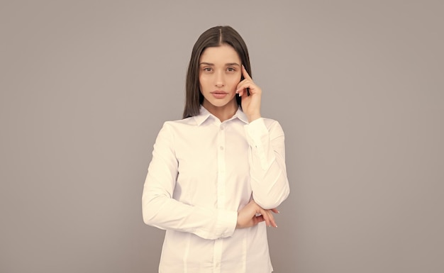 Thinking businesslady in white shirt on grey background ceo