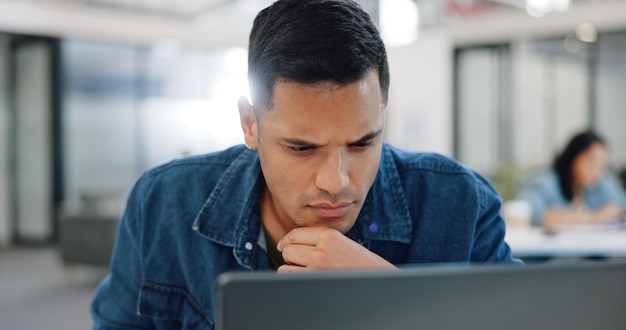 Thinking confused and man at laptop writing notes for project planning at web design company Professional ux employee at office working thoughtful and focused on email idea for client