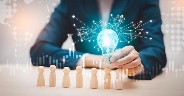 Thinking and creative, Businessman hand holding light bulb on the wooden people, Teamwork and idea concept, Successful team leader, Businessman hand choose people standing out from the crowd.