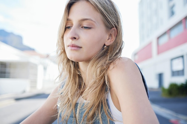 Thinking girl in the street in the city sad expression on her face Young student sitting in road in urban town with mindful thoughts depression and mental health Woman alone sadness and stress