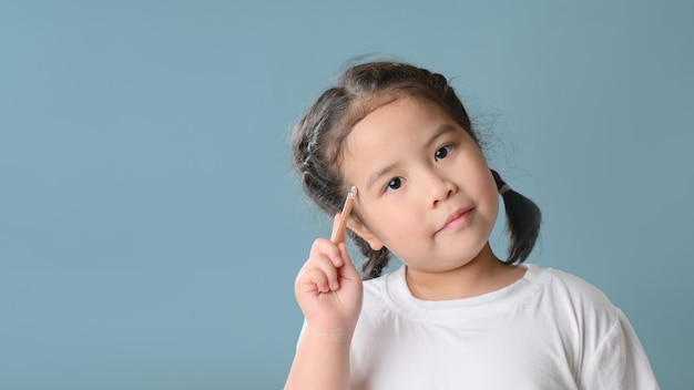 Thinking little asian child girl on blue background. Child thinking. Brainstorming and idea concept. Education concept.