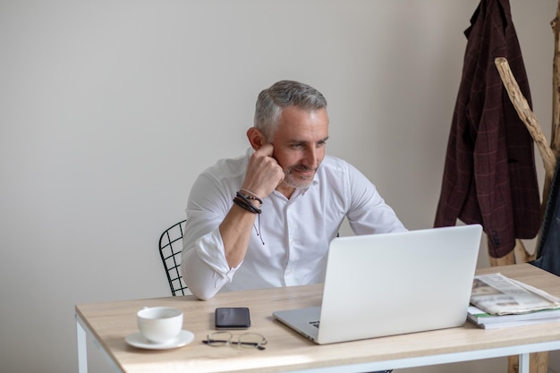 Thinking man looking at laptop sitting at table