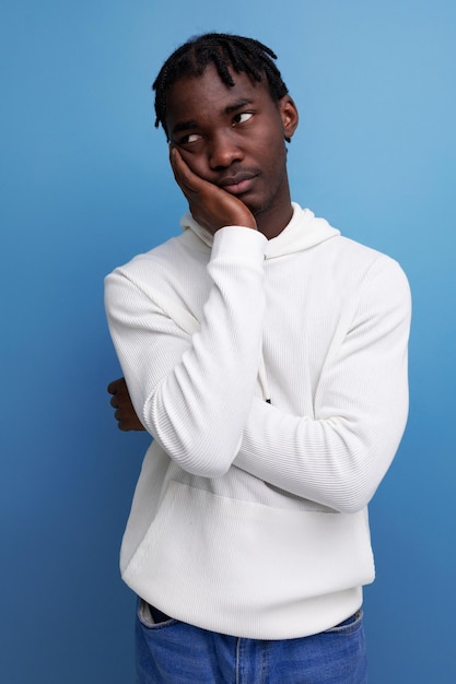 Thinking model darkskinned young brunette man looks away in a white sweater