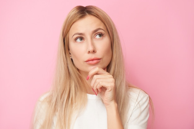 thinking person in white shirt, dreamy girl thought and looking up isolated on pink