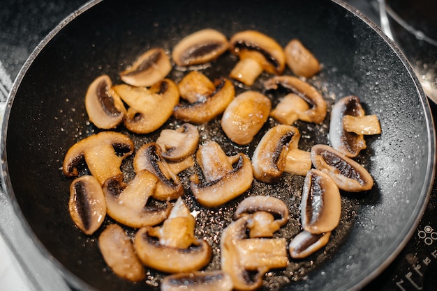 Thinly sliced fresh raw mushrooms are fried in a pan close-up. Healthy diet.