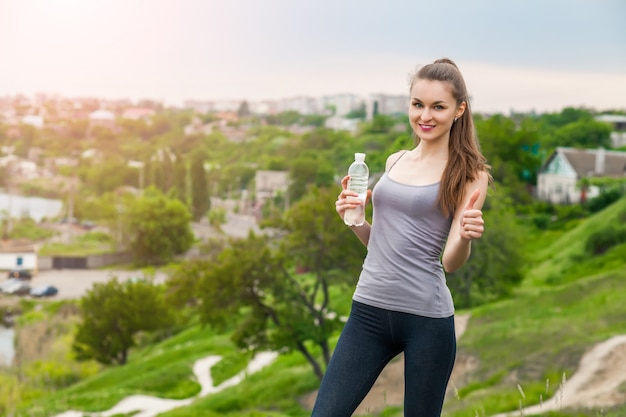 Thirsty fitness girl holding bottle of water