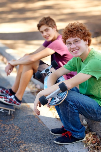 This beats sitting around indoors Portrait of two young skateboarders sitting beside a road