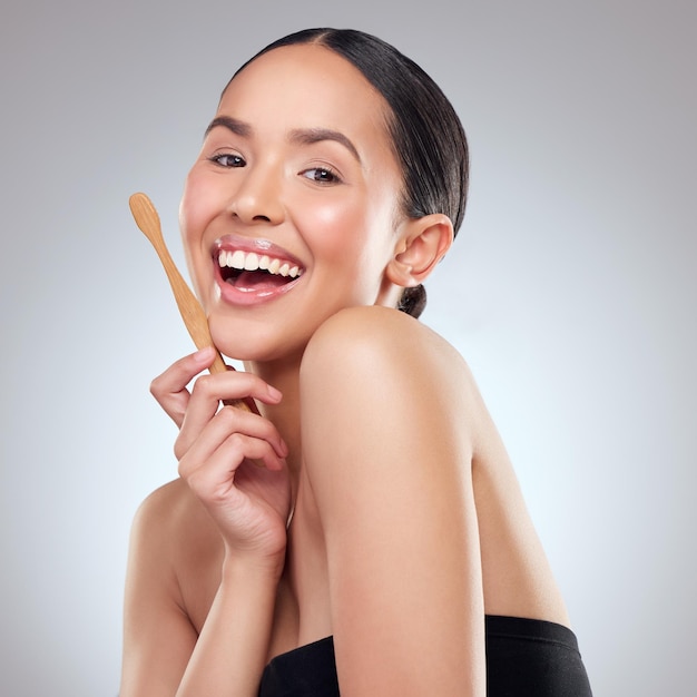 This brush has been sustainably sourced Studio portrait of a beautiful young woman brushing her teeth against a grey background