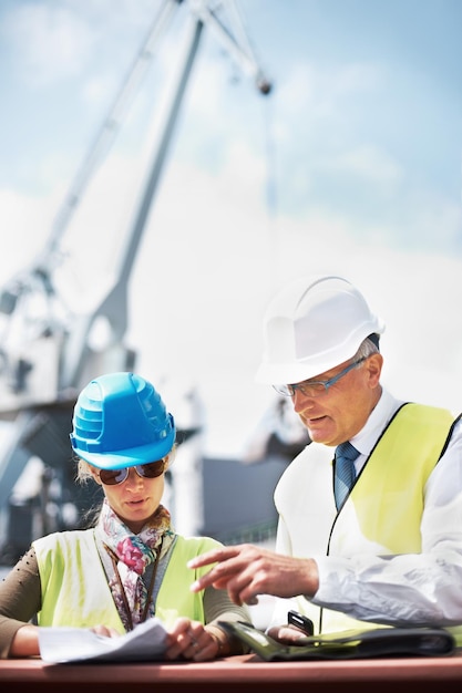 This copyspace will help promote your business Two dock workers holding paperwork while standing in the shipyard